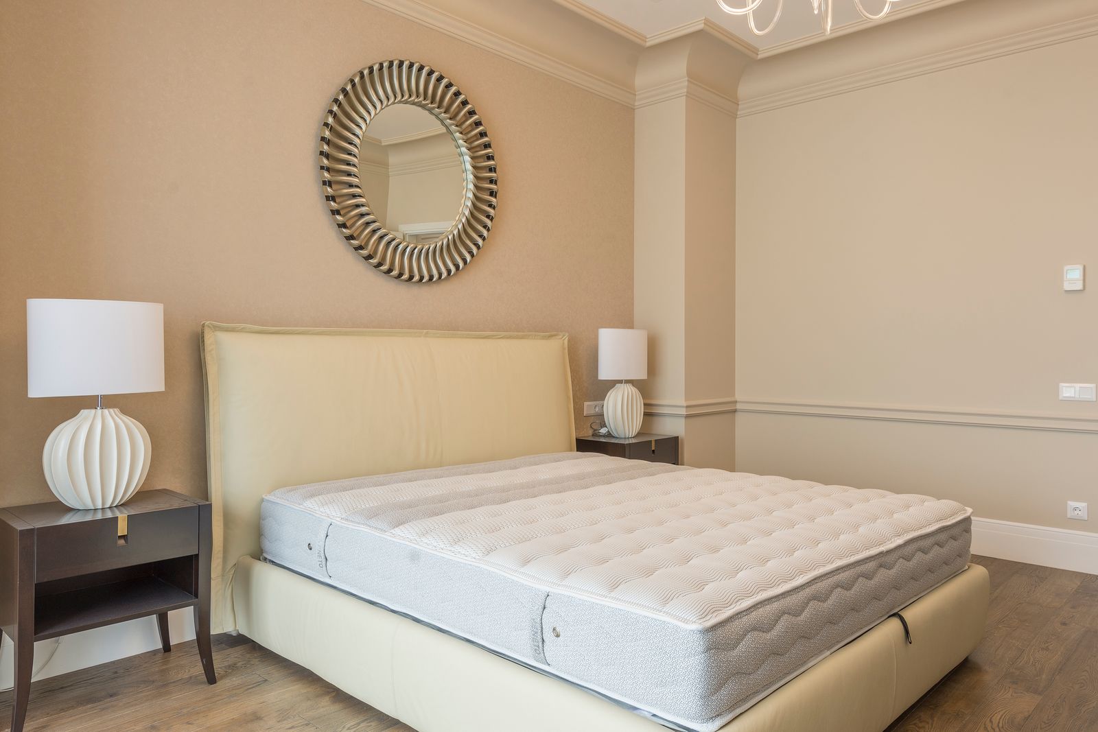 Bedroom interior showing a bed frame and headboard against the wall, the type of surface where residual bed bug treatments are applied