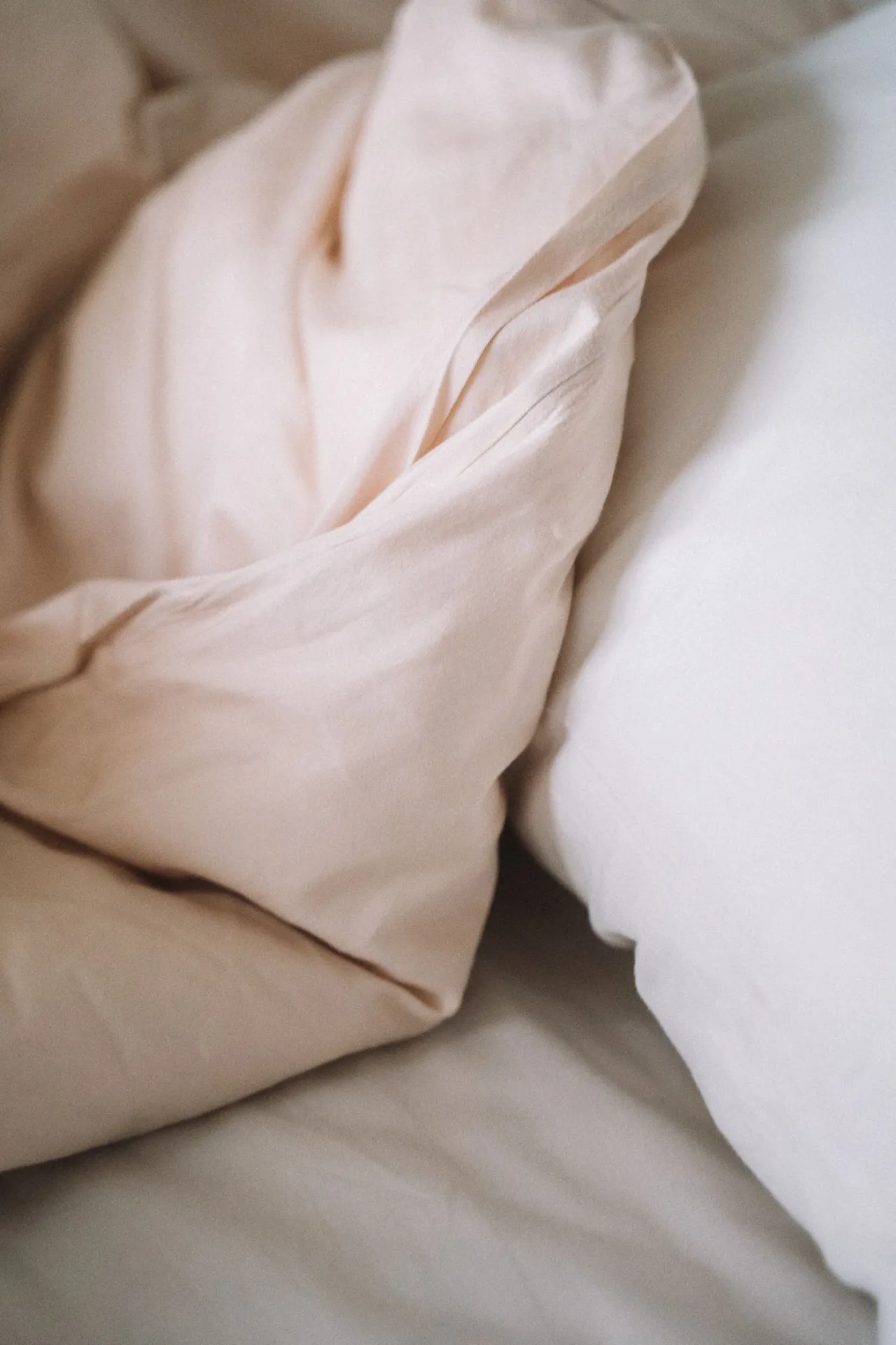 Crumpled white bed sheet where early bed bug stains show up as small rust-colored or dark spots